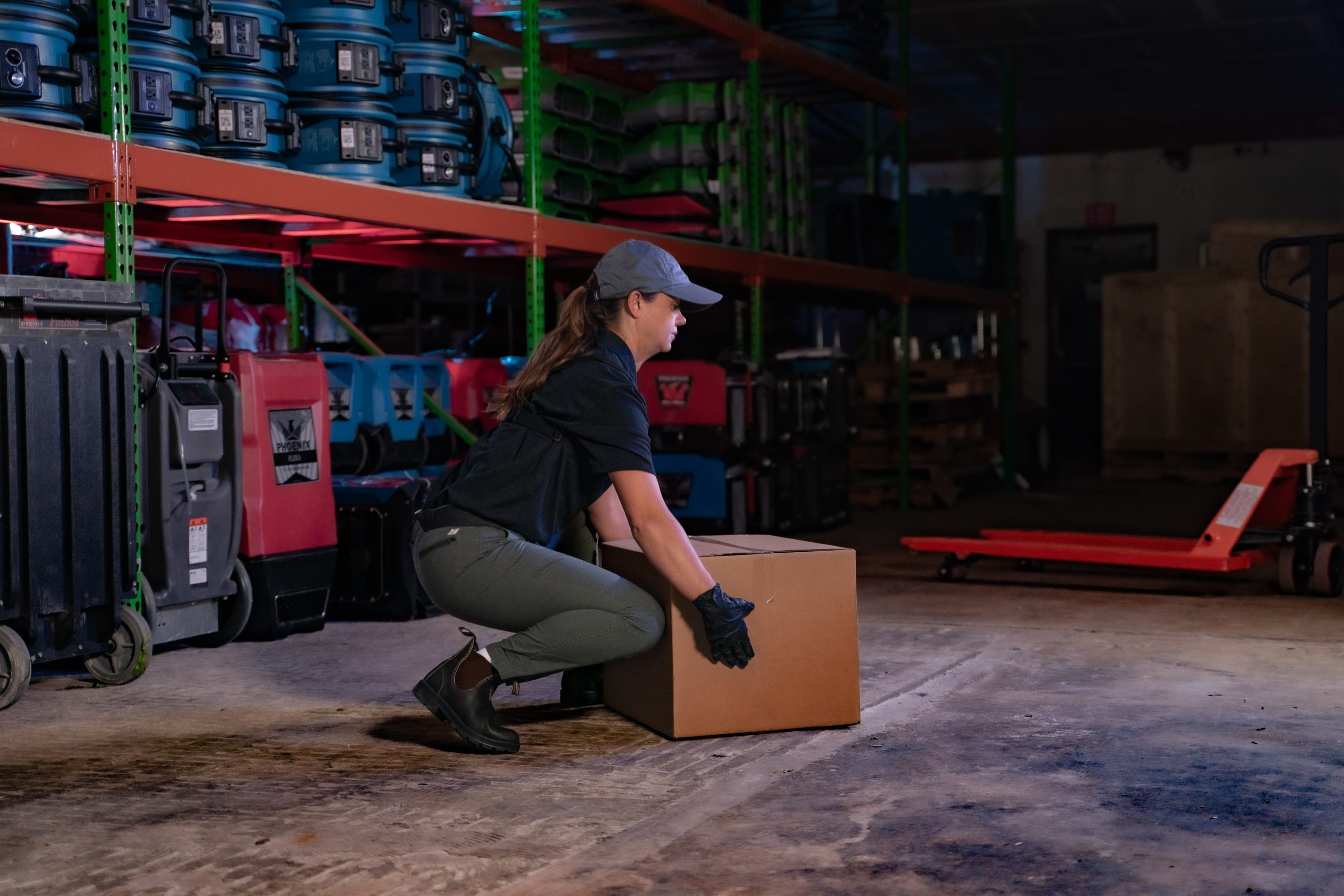 Female worker uses proper ergonomic technique to carefully lift a box from the floor.